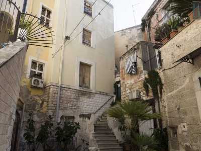 ...il cortile presenta una scalinata che a met� percorso devia sulla destra e porta in una delle case color pastello che la circondano